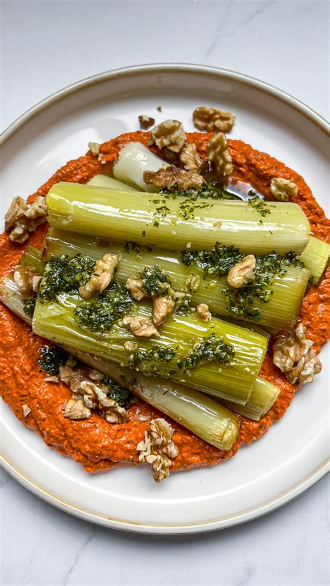 Puerros asados en una bandeja con un cuenco de salsa romesco