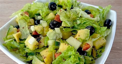 Ensalada de piña y lechuga, con toques frescos y coloridos, servida en un bol de madera
