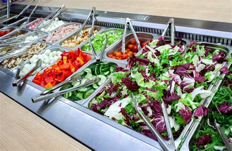 Mesa con diferentes opciones de ingredientes frescos para personalizar ensaladas, incluyendo frutas y verduras