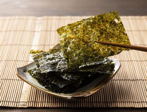 Secuencia de imágenes mostrando cómo se extiende el arroz sobre el nori y se añade el relleno.