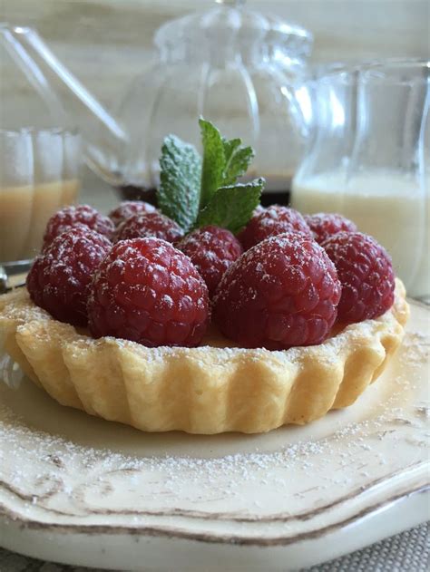 Foto principal de una tartaleta de frambuesas, con algunas frambuesas frescas alrededor