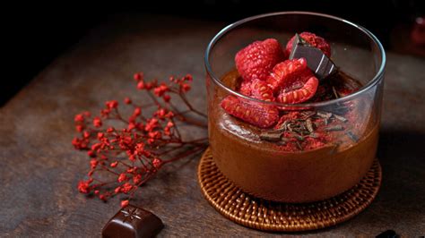 Primer plano de una mousse de chocolate y café con frutos rojos y ralladura de naranja