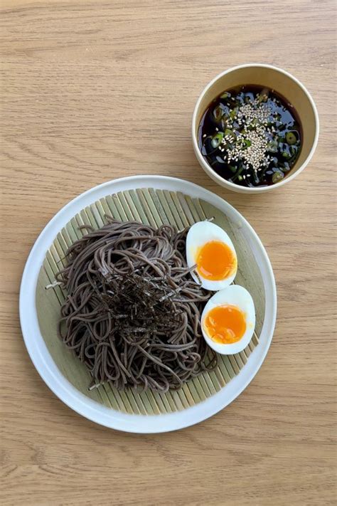 Bol de fideos soba fríos con condimentos y un pequeño recipiente con mentsuyu