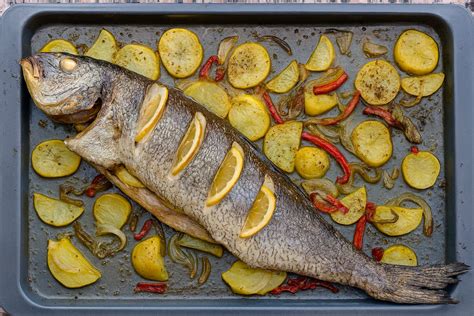 Fotografía paso a paso del montaje de la corvina con base de patatas y verduras en fuente de horno.