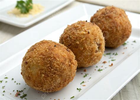 Imagen de bolitas de arroz doradas y crujientes servidas en un plato decorado con perejil fresco