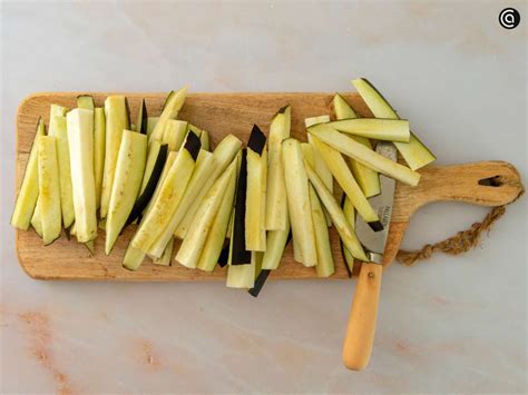 Berenjenas cortadas en rodajas y dispuestas en un escurridor con sal.