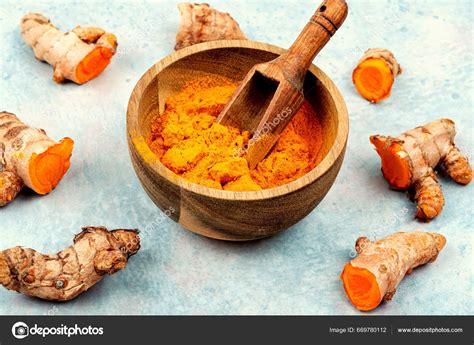 Raíz de cúrcuma fresca y cúrcuma molida en un tazón