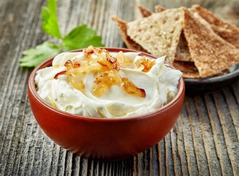 Foto de un cremoso dip de queso y cebolla caramelizada servido con tostadas