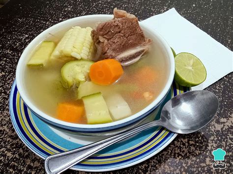 Plato de caldo de verduras fresco y un recipiente hermético al lado
