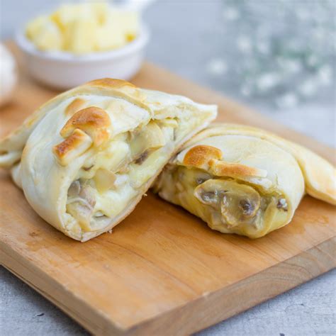 Manos cerrando una empanada con relleno de champiñón y queso