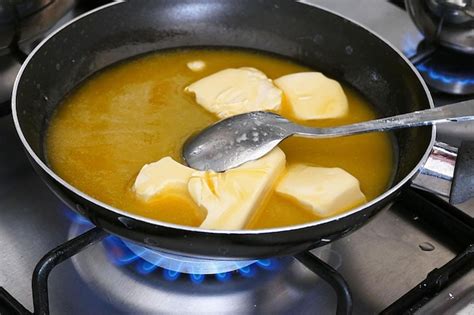 Cacerola pequeña con mantequilla derritiéndose y ajo picado, preparando la base de la salsa.