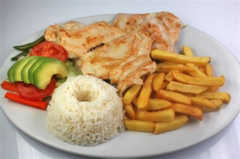 Foto: plato infantil colorido con pollo a la plancha, trozos de tomate y maíz, presentado de forma atractiva.