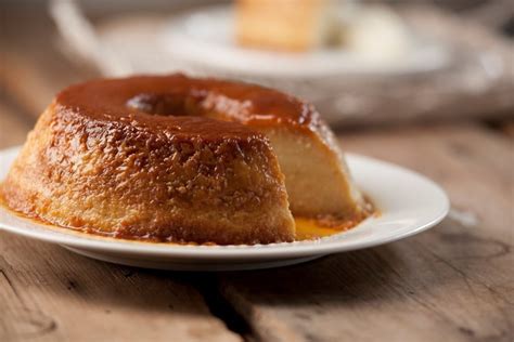 Imagen de un budín de pan francés desmoldado sobre un plato, con el caramelo líquido cubriendo la parte superior y los lados.