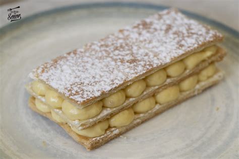 Milhojas clásica con capas de hojaldre y crema pastelera espolvoreada con azúcar glas