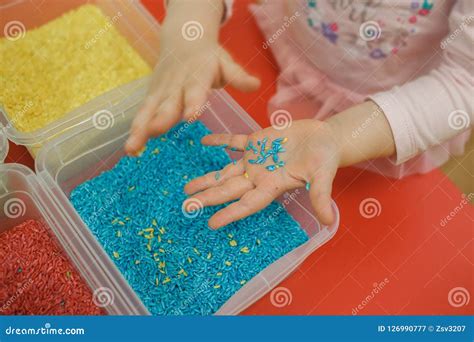 Niño jugando en una mesa sensorial con arroz de colores