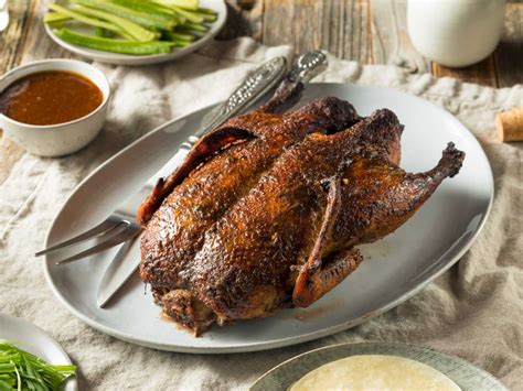 Pato laqueado asándose en el horno sobre una rejilla con bandeja