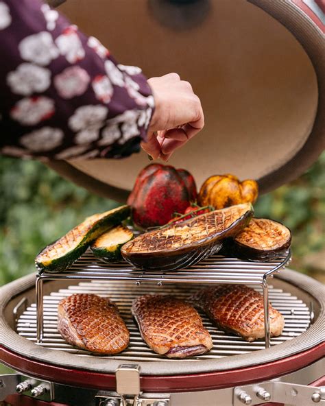 Paleta de cerdo cocinándose en un kamado, con humo aromático