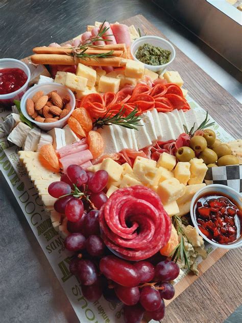 Imagen de una tabla de picoteo bien decorada con quesos, frutas, embutidos y frutos secos dispuestos de forma estética