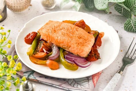 Plato de salmón al horno con una variedad de verduras asadas