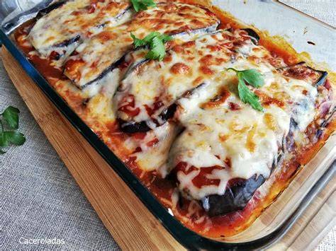 Bandeja de horno con capas de berenjena, salsa de tomate y queso, lista para hornear.