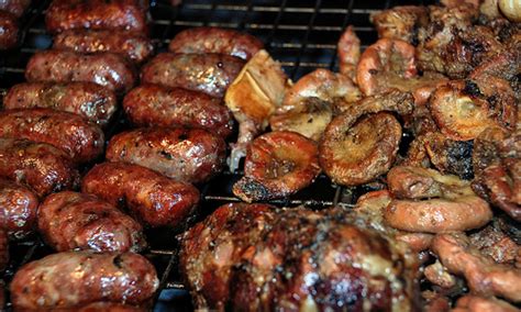 Parrilla argentina con diferentes cortes de carne y achuras cocinándose sobre brasas
