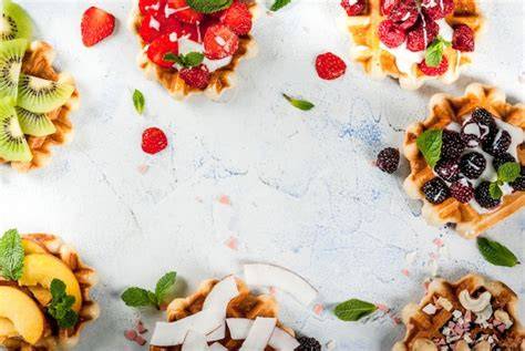 Varias tortas pequeñas decoradas con diferentes coberturas como frutas frescas, chocolate y glaseado blanco.
