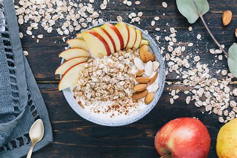 Primer plano de un desayuno nutritivo con yogur, avena, trozos de manzana y frutos secos