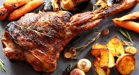 Cordero asado al horno en una bandeja, con hierbas aromáticas