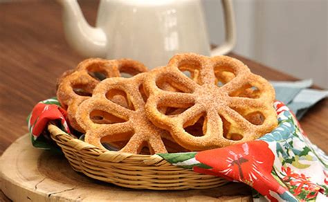 Imagen de una bandeja con buñuelos de viento dorados y espolvoreados con azúcar glas