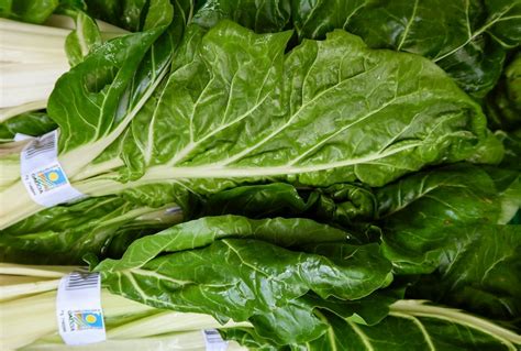 Foto de acelgas y espinacas frescas en un mercado de agricultores