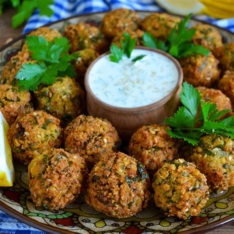 Falafel servido en un plato con salsa de yogur y pan de pita.