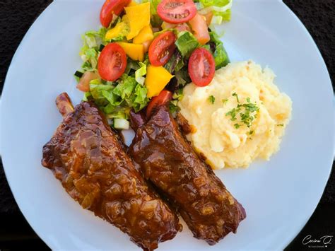 Plato de costillas de cerdo con salsa BBQ y acompañamientos