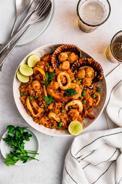 Mesa con varios ingredientes para arroz con mariscos: ajíes frescos, mariscos variados, arroz crudo, vino blanco