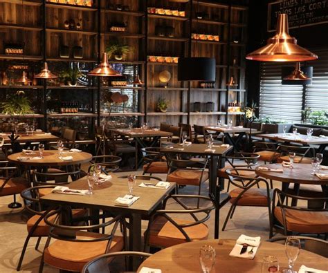 Interior elegante de un restaurante de carnes con parrilla a la vista y cava de vinos