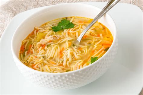 Foto de un plato de sopa de pollo caliente con verduras y cilantro, servido en un tazón tradicional.