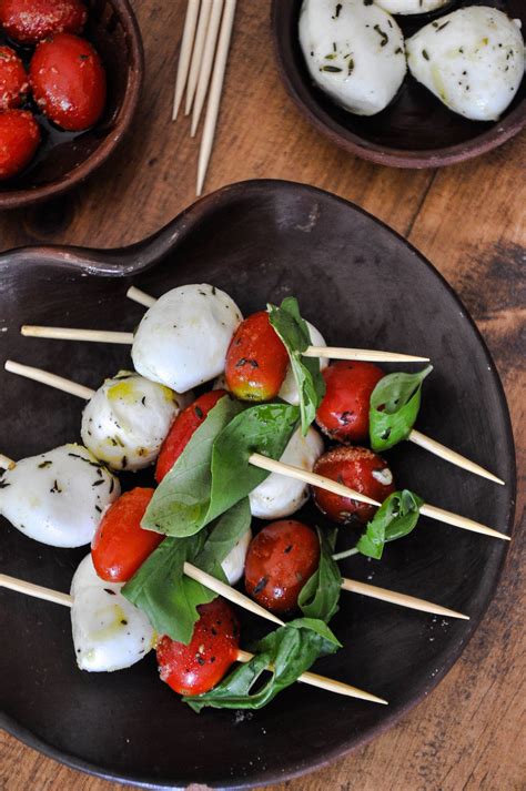 Primer plano de brochetas caprese con tomate cherry, mozzarella y albahaca