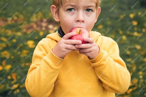 Niño comiendo una manzana con una sonrisa en un entorno luminoso y natural