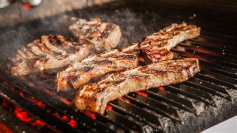 Asado de tira cocinándose en la parrilla con brasas
