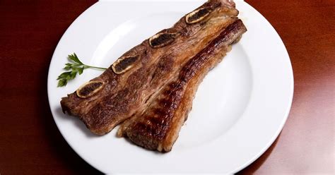 Asado de tira ya cocido en una tabla de madera, listo para servir