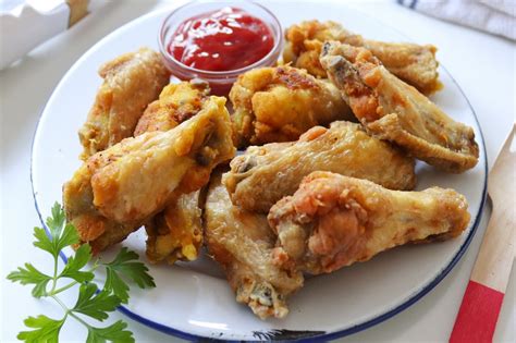 Foto de alitas de pollo fritas doradas y crujientes con acompañamientos