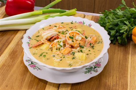 Foto de una sopa de camarón humeante en un tazón tradicional, con camarones y verduras visibles