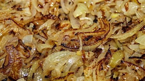 Primer plano de cebollas caramelizándose en una sartén.