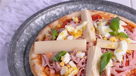 Fotografía gastronómica de una pizza de jamón y palmitos recién horneada, mostrando la textura de los palmitos y el fundido del queso.