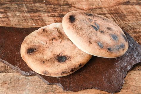 Ilustración de la preparación tradicional de tortillas al rescoldo sobre brasas y cenizas