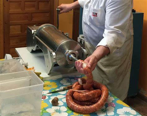 Persona embutiendo longanizas con una máquina manual.