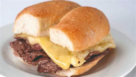Fotografía de un sándwich Barros Luco servido en un pan marraqueta con carne y queso derretido.