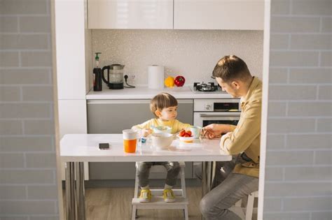 Padre alimentando a su bebé en la mesa, fomentando la autonomía