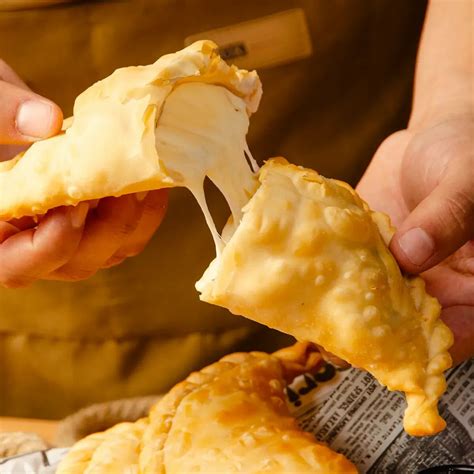 Foto de una empanada de queso frita con el queso derretido saliendo