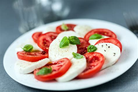 Bolas de mozzarella fresca en un plato, con hojas de albahaca y tomates cherry