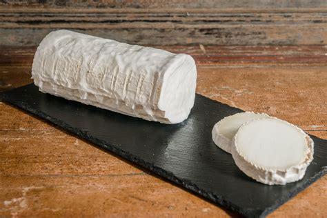 Rulo de queso de cabra cortado en rodajas sobre una base de madera